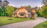 Modest country home on a wooded Grayson County-style lot at warm late-afternoon light, green lawn and driveway under a soft sunset sky—no people, no text