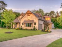 Modest country home on a wooded Grayson County-style lot at warm late-afternoon light, green lawn and driveway under a soft sunset sky—no people, no text