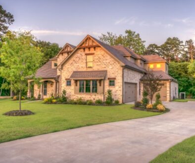 Modest country home on a wooded Grayson County-style lot at warm late-afternoon light, green lawn and driveway under a soft sunset sky—no people, no text