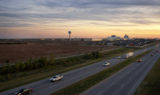 U.S. 75 corridor at dusk near Sherman, with prairie, a water tower, and industrial lights on the horizon.