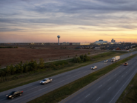 U.S. 75 corridor at dusk near Sherman, with prairie, a water tower, and industrial lights on the horizon.