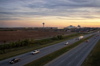 U.S. 75 corridor at dusk near Sherman, with prairie, a water tower, and industrial lights on the horizon.