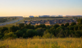 North Texas landscape at golden hour showing new suburban homes, highway, and industrial campus on the horizon in Grayson County