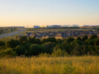 North Texas landscape at golden hour showing new suburban homes, highway, and industrial campus on the horizon in Grayson County