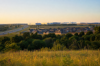 North Texas landscape at golden hour showing new suburban homes, highway, and industrial campus on the horizon in Grayson County