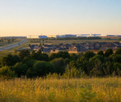 North Texas landscape at golden hour showing new suburban homes, highway, and industrial campus on the horizon in Grayson County