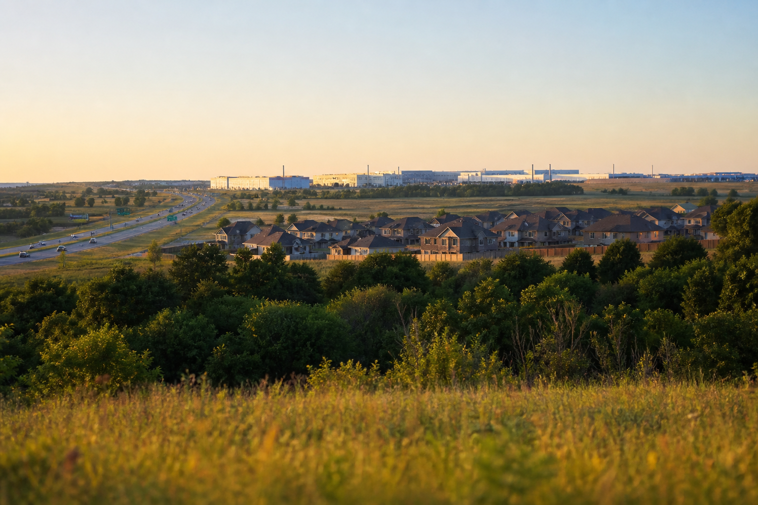 North Texas landscape at golden hour showing new suburban homes, highway, and industrial campus on the horizon in Grayson County