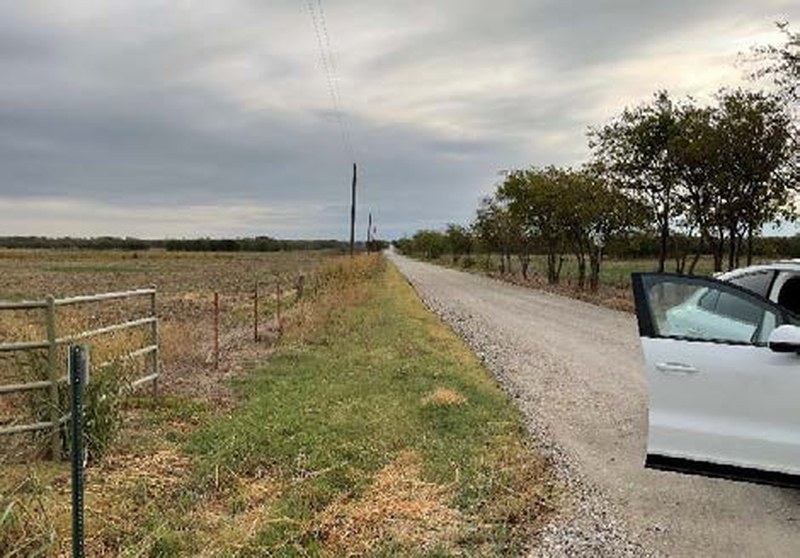 Two-lane gravel Mobberly Road facing east past ranch fencing along the Bryson Ranch property in Pilot Point TX