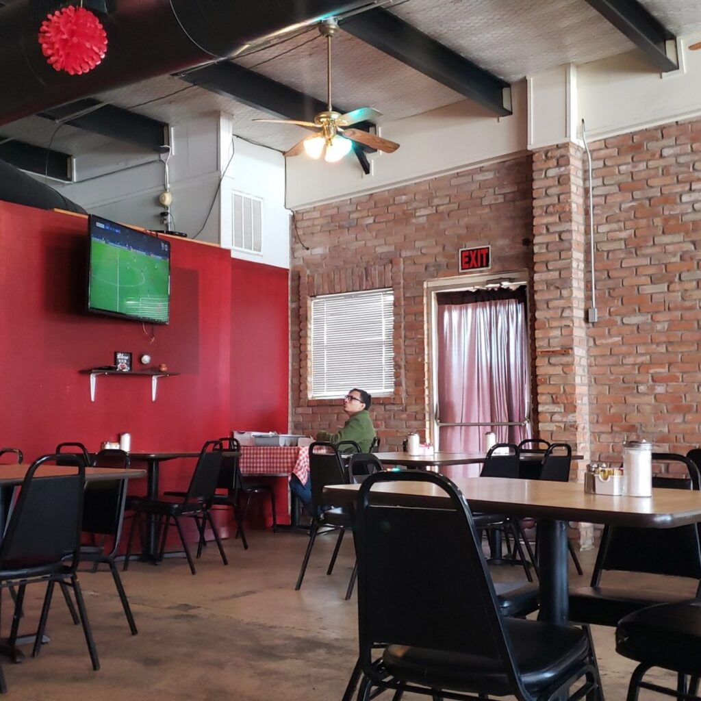 Red and exposed-brick dining room with tables and chairs inside Gabriela's Mexican Cocina in Howe