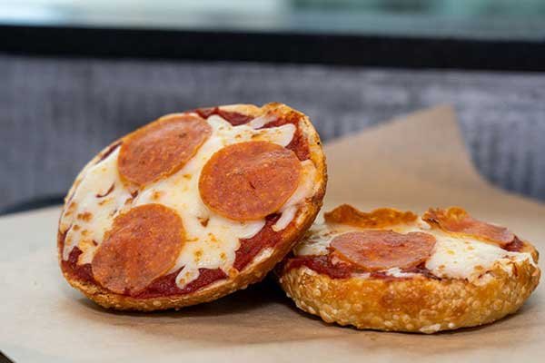 Two pepperoni pizza bagel halves with melted cheese, one of the Legacy Bagels exclusives