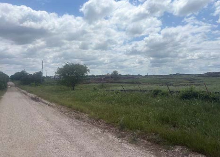 Gravel road running past pasture and a wire fence in Platinum Ranch's first phase in Gunter TX, photographed for the May 2026 appraisal