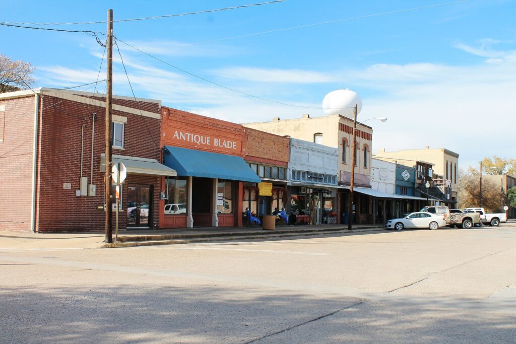 A row of brick storefronts in Van Alstyne, Texas, with a water tower behind them
