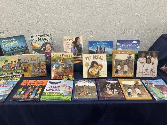 Table of Native children's picture books including Fry Bread, Jingle Dancer, and Powwow Day, from the Sundrop Books ribbon cutting photos in Denison